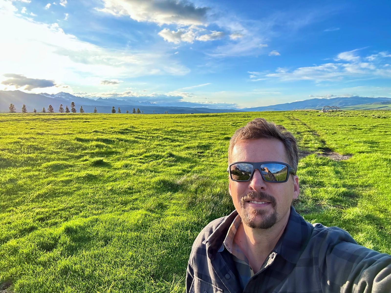 David Tedesco in a meadow in the Sawtooth Valley, with the Sawtooth Mountains in the distance